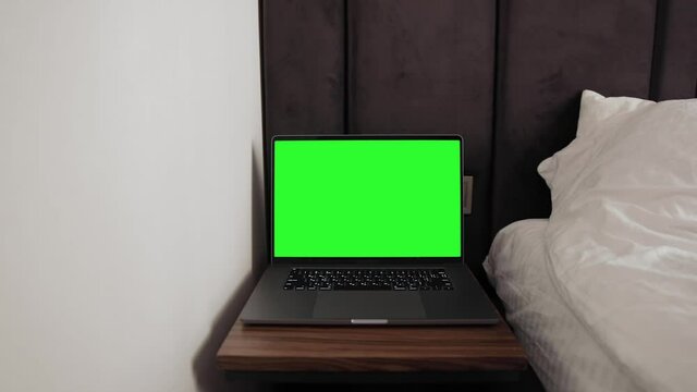Close up shot of modern chroma key green screen MacBook Pro 16 inch laptop computer set up for work on desk at night - remote work, technology concept, video template. Hotel room environment 