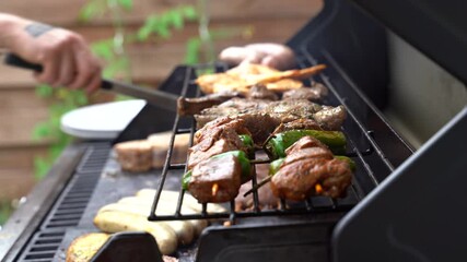 Close up shot of man using tongs to barbeque meat and sausages or bratwurst on a grill in backyard - Powered by Adobe