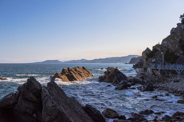 The huge waves crashing into ston island against the blue sky and horizon at summer sea shore.