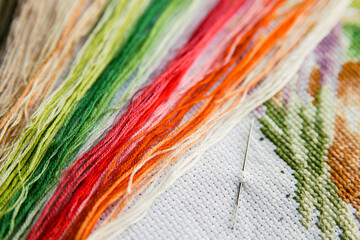 Set of colored threads for embroidery on a white embroidered canvas. - 369669324
