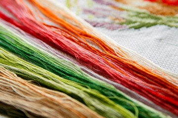 Set of colored bright threads for embroidery on a white embroidered canvas. - 369669350