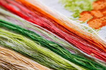 Colored bright threads for embroidery on a white embroidered canvas. - 369669393