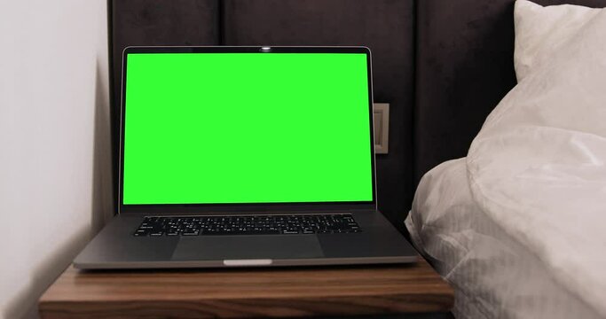 Dolly shoot of the laptop computer stying on the table in hotel room. Monitor with green screen. Good choice for your advertising placement.