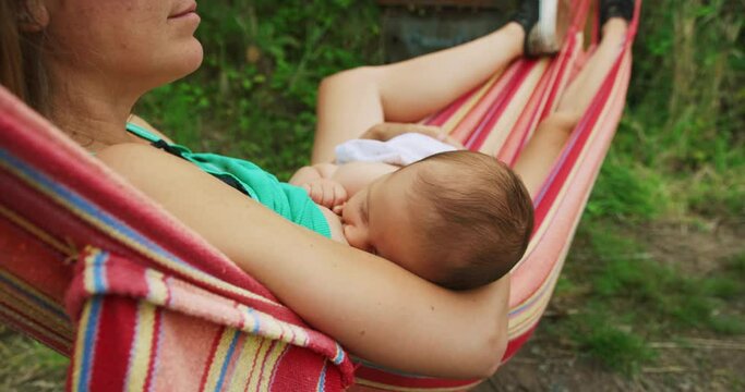 Mother breastfeeding baby in hammock