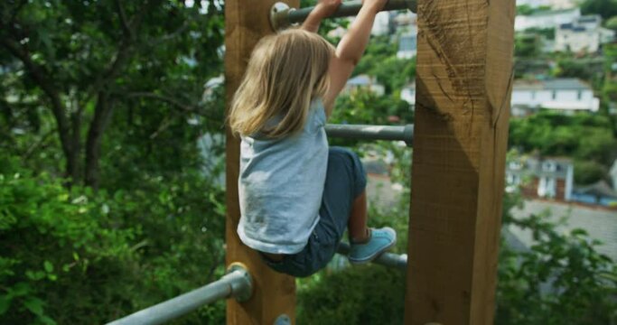 Preschooler climbing and hanging from bars of calisthenics gym