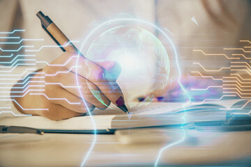 Double exposure of woman's writing hand on background with brain hologram. Concept of brainstorming.