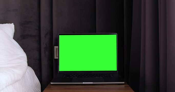 Apple MacBook Pro 16 inch Laptop with keyed chroma key green screen standing near bed, woman hand opening notebook, online travel booking.
