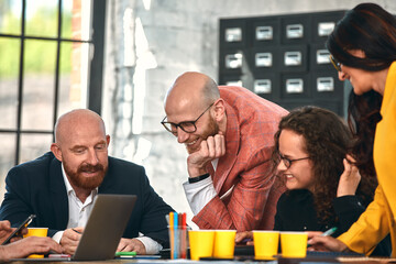 Beautiful business people are using gadgets, talking and smiling during the conference in office. Selective focus