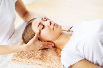 Fototapeta na wymiar Young beautiful girl having face massage relaxing in spa salon.