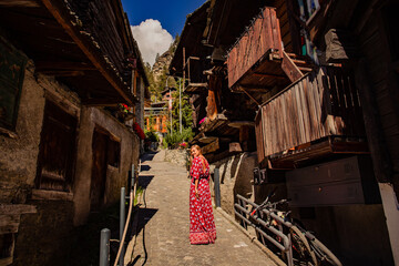 Naklejka premium Beautiful blonde girl in red dress posing on streets of tourist city
