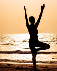 young woman doing yoga on the beach