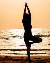 young woman doing yoga on the beach