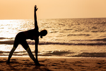 young woman doing yoga on the beach
