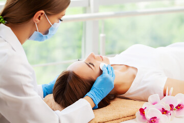 Young beautiful girl having face massage relaxing in spa salon.