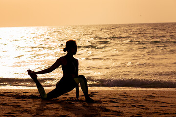 young woman doing yoga on the beach