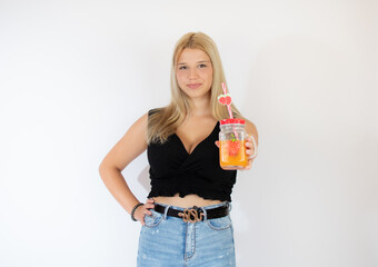 Beautiful blonde girl in black shirt showing a fruit juice