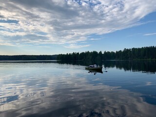 Boat on the lake, surface of the water like a mirror, cloudy sky