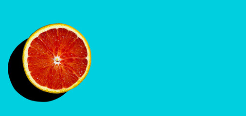 Top view of ripe blood red orange citrus fruit on turquoise background. Hard light. Banner, copy space.
