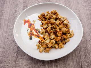 Fried Turkish Manti with red pepper, tomato sauce, yogurt and mint. Plate of traditional Turkish food. Top view