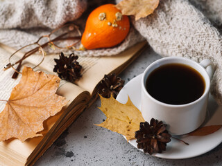 a Cup of hot coffee on the table with a knitted scarf and an old book. the comfort of home in autumn