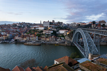 Porto view, with Dom Luís Bridge and Douro river. Sunset, blue sky and clouds. Boats on the river
