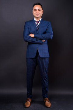 Portrait of happy young handsome Indian businessman in suit