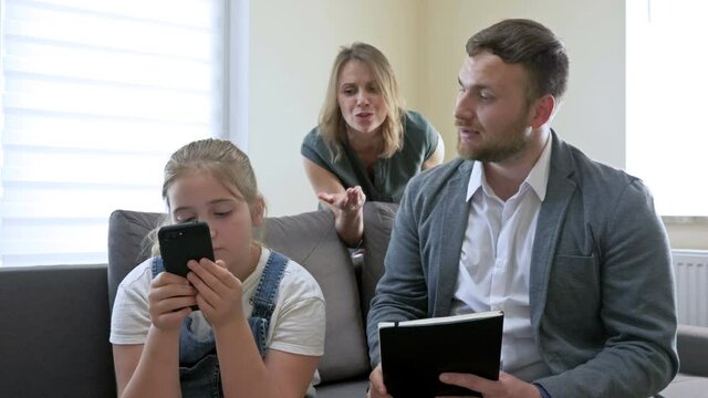 Problems of parenting in the family. Parents very much scolding a teenage daughter for something. The girl looks indifferently at the phone screen and angers her parents even more.