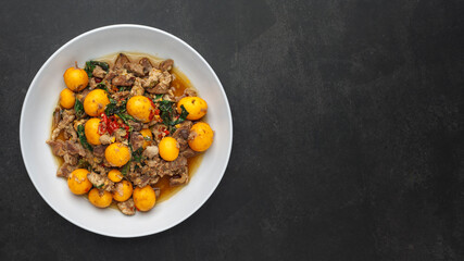 hot and spicy stir fried chicken ovary egg with chicken entrails and basil on dark grey texture background with copy space, Thai local street food