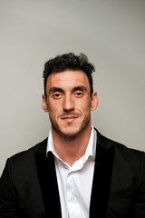 Close up portrait of a man 30-34 years old in a white shirt and a black jacket on a gray background. 