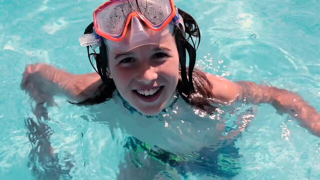 Child with a swimming mask in a swimming pool