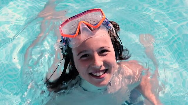 Child with a swimming mask in a swimming pool