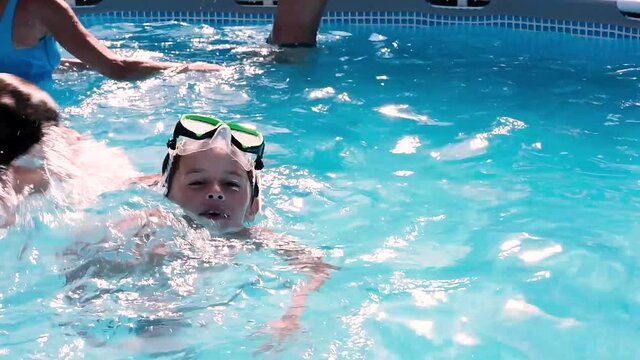 Child swimming in a swimming pool while people practicing water aerobics
