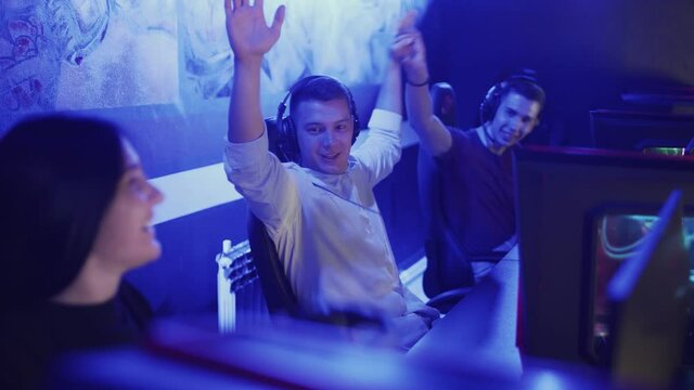 Team of teenage cyber sport gamers win the multiplayer PC video game on eSport tournament and give five to each other