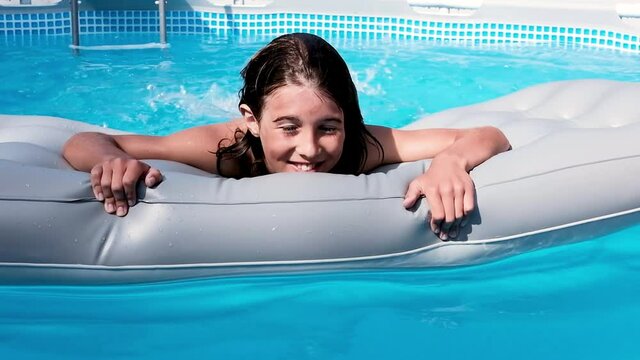 Child having fun swimming and relaxing in the blue water of a swimming pool while cooling off on a summer day