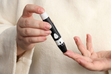 close-up female hands, woman makes test with lancet pen and glucometer, Medicine, glycemia, healthcare and medical concept