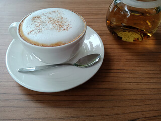 Cappuccino in a white cup and hot tea