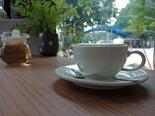 Cappuccino in a white cup and hot tea