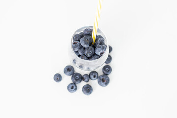 
Blueberries on a white background. And also in a glass with a yellow tube. On a gray background.
