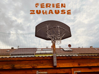 Basketballkorb vor Hausdächer viel Himmel 