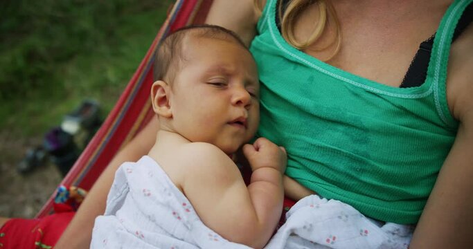 Young motrher relaxing in hammock with her baby
