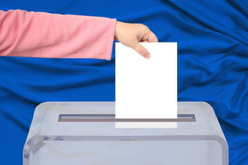 Voter’s female hand lowers the ballot in a transparent ballot box on the background, concept of state elections, referendum