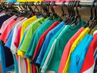 A lot of new t-shirts on hangers in the stores showroom..Training form on hangers on the shop window of a sports shop.