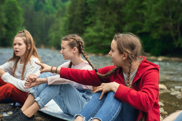 Fototapeta premium Girls sitting on mats on river beach.