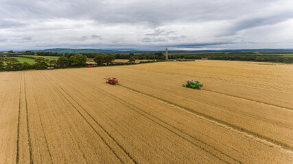 Fototapeta na wymiar Combine harvesters cultivating wheat fields in rural Ireland
