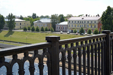 On a blurred background old buildings of Rybinsk, Russia on the embankment of the Volga River. The wrought-iron fence of the bridge in the foreground.