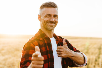 Image of smiling man showing thumb up and pointing finger at camera