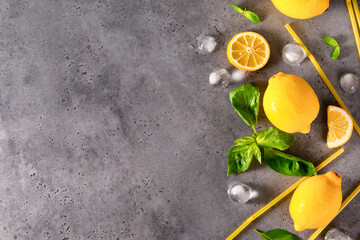 green Basil, ice cubes, yellow tubes  , yellow whole lemons and slices, on a gray