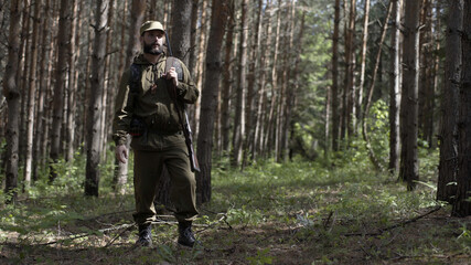 Man takes aim while standing from hunting rifle. Man in comfortable camouflage clothes hunter...