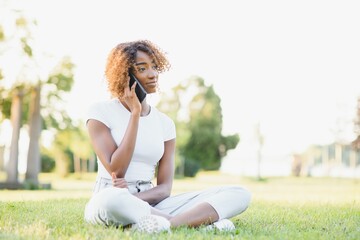 people, technology and leisure concept - happy african american young woman calling on smartphone outdoors