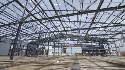 Modern storehouse construction site, structural steel structure of new commercial building against. Construction of modern factory or warehouse.